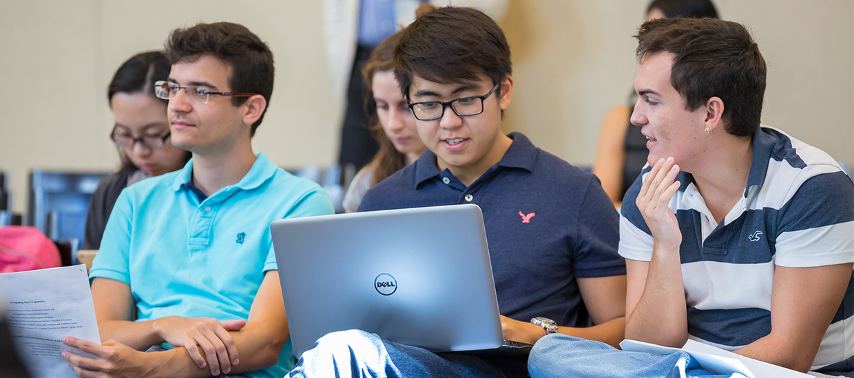 Group of students talking and using a laptop