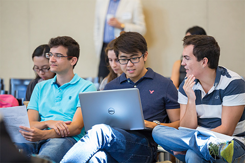 Group of students talking and using a laptop